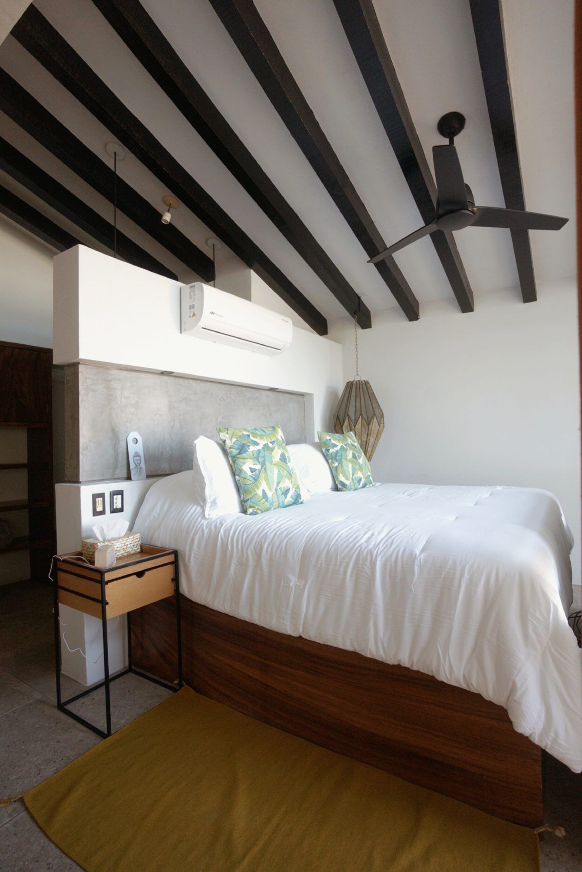 Vaulted bedroom with timber beams and gold headboard